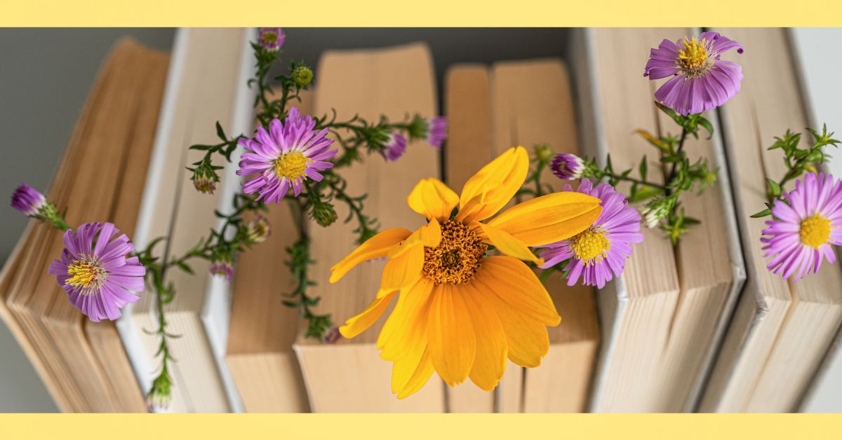 row of books with purple flowers and one with a yellow flower